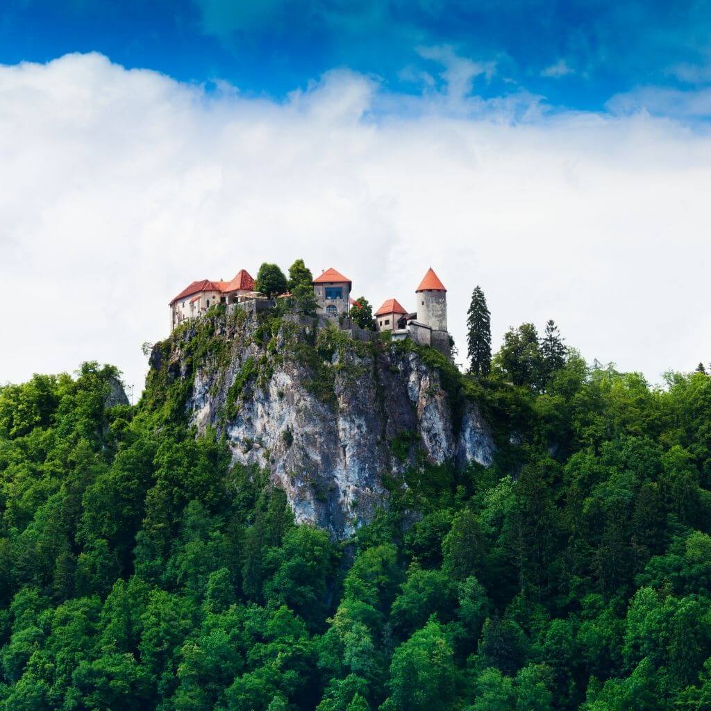 bledi-sziklas-var-a-felhok-elott-a-zold-erdobol-kiemelkedve-szlovenia